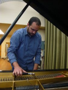 An Image Of Shane Emrich Tuning A Grand Piano Put On By Emrich Piano Service